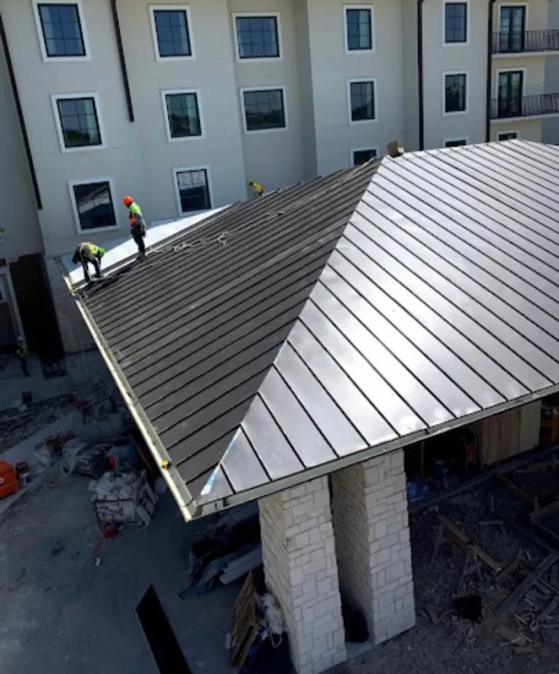 Crew installing standing seam metal roof panels on a commercial project in Seward